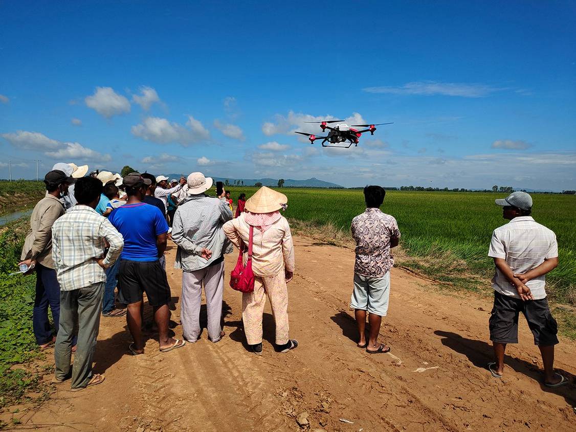 Local farmers watched the demonstration of XAG agricultural drone spraying crops