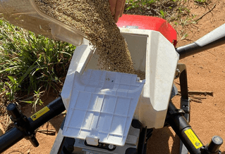 Drone loaded with containers full of grass seeds
